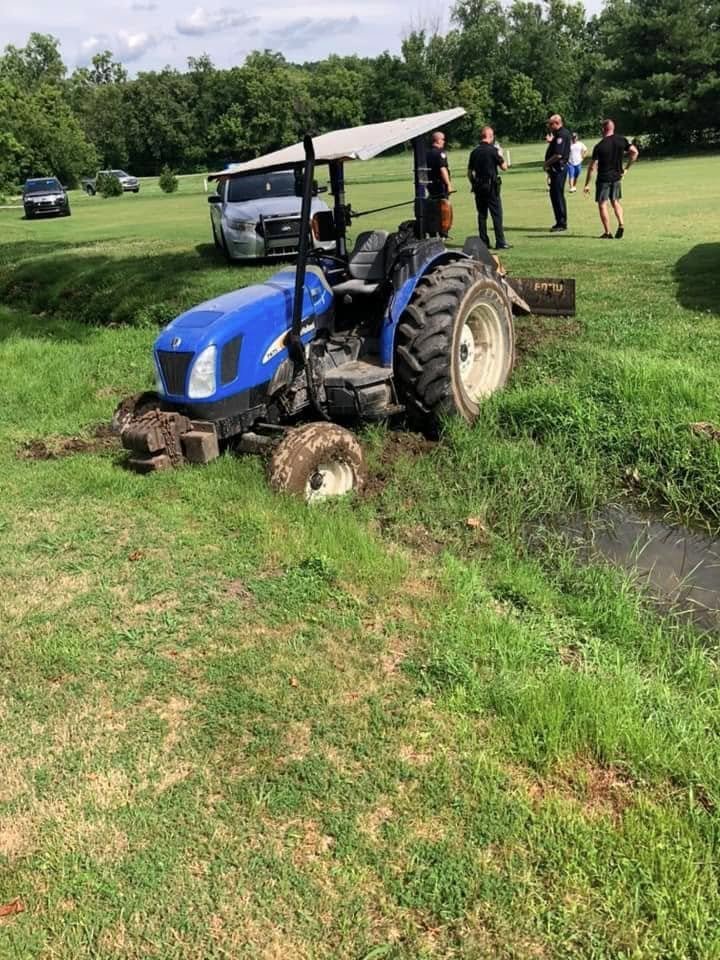A tractor stuck in the mud near a pond as police officers investigate at Berea Country Club